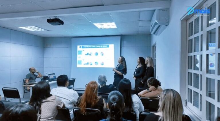 Equipe acompanhando uma apresentação projetada em sala de reunião.