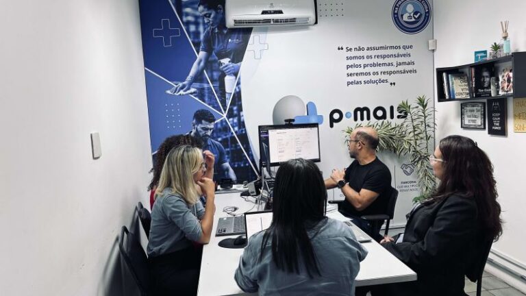 Profissionais reunidas ao redor de uma mesa no escritório da PMais.